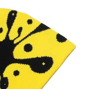 Macro detail of high-density knit beanie fabric with yellow and black abstract patterns