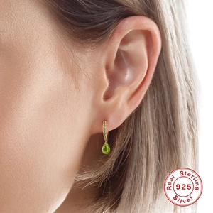 Close-up of S925 sterling silver drop earring with green crystal on a female model