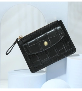 Close-up of black crocodile embossed leather card holder with gold zipper on blue props