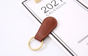 Detailed close-up of brown PU leather keychain with gold metal ring on a 2024 calendar