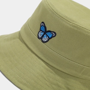 Close-up of blue butterfly embroidery on light green cotton twill bucket hat