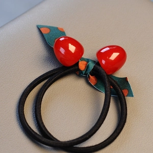 Elastic hair tie featuring red resin cherries and a green polka dot ribbon bow