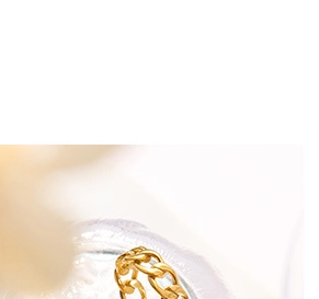 Détail d'une bague chaîne dorée avec incrustation de zircon et de nacre blanche élégante