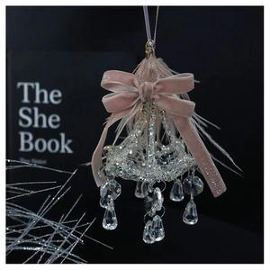 Detail of crystal chandelier ornament with pink velvet bow and elegant feather accents