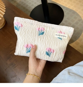 Detailed embroidery of pink tulips and green leaves on a cream canvas makeup bag