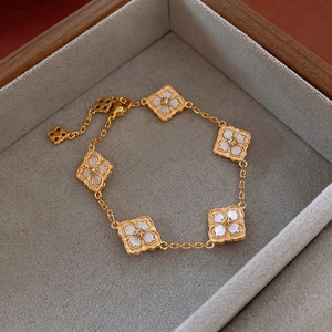 14K gold plated clover bracelet with white mother-of-pearl floral charms in a jewelry box