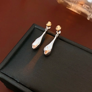 Polished gold and silver two-tone teardrop dangle earrings on jewelry box
