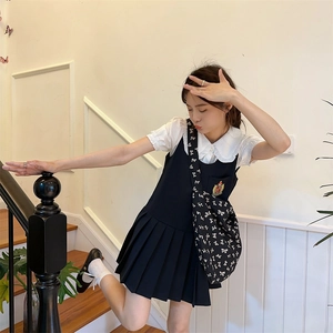 Detail of JK style white ruffle collar shirt and navy pleated dress with bow crossbody bag