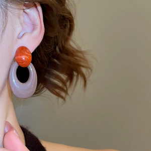 Detail of vintage acrylic oval earrings with orange marble stud and purple resin hoop