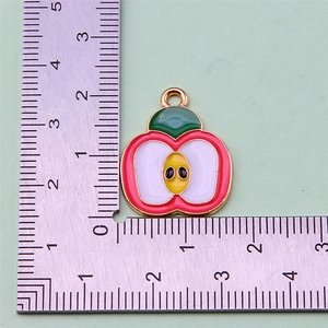 Macro shot of an apple enamel pendant on a metal ruler showing 1.8cm scale size