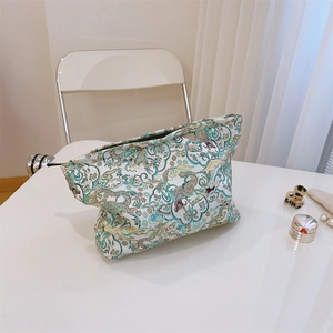 Detail of teal jacquard makeup bag showing traditional dragon and cloud brocade patterns