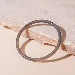 Vue détaillée d'un bracelet en acrylique gris translucide sur un support en pierre texturé
