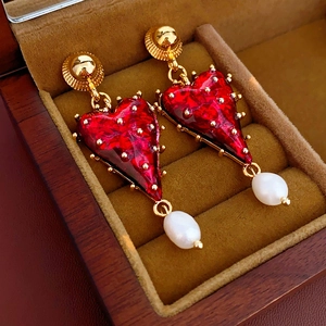 Detail view of vintage red heart earrings with white pearls in a velvet jewelry box
