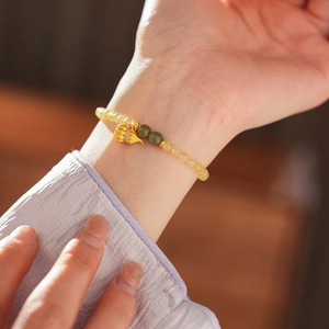 Detailansicht eines Perlenarmbands aus gelbem Quarz mit einem goldenen Fuchs-Anhänger