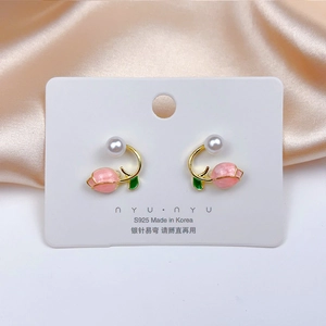 Detailed macro view of pink floral enamel earrings with white pearls and gold details