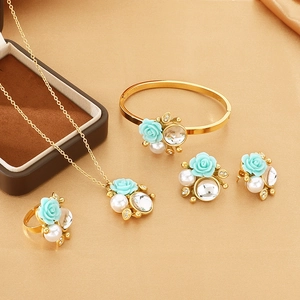 Exquisite golden jewelry set detail featuring light blue roses, pearls and crystals