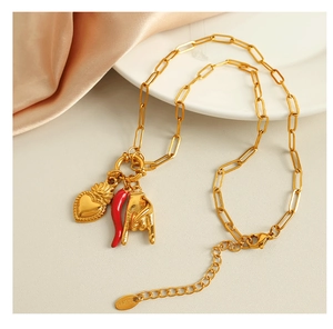 Close-up of gold chain necklace with red chili, heart, and rock gesture pendants