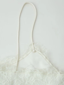 Détail de la dentelle blanche avec bordure en cils et tissu satiné sur les bretelles