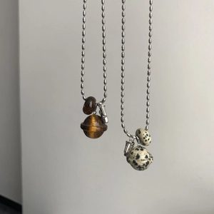 Detail of tiger eye and dalmatian stone pendants in planet shape on silver bead chains