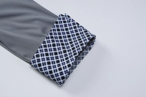 Détail d'un haut gris en maille côtelée avec poignets à carreaux et col polo élégant