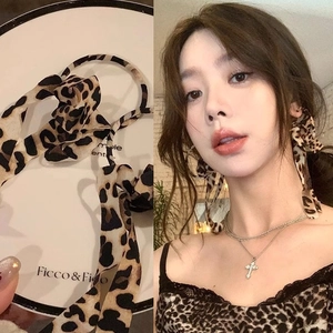 Detail showing leopard print hairband and silk camisole with a cross pendant necklace