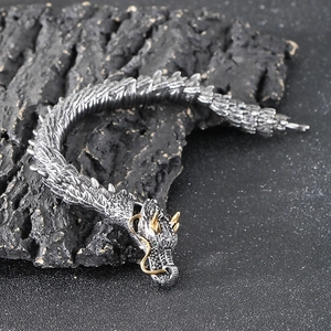 Detailed macro shot of vintage silver dragon bracelet with golden horns and green eyes