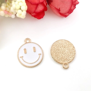 Detailed macro view of a round yellow enamel smiley face pendant and golden textured charm