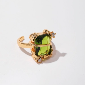 Macro detail of gold vintage ring with emerald green stone and lava texture finish