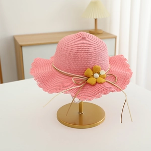 Detailaufnahme von rosa Mädchen-Strohhut mit gelber Stoffblume und gewellter Krempe