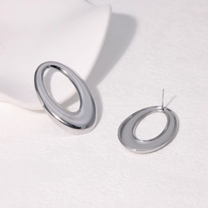 Macro shot of silver oval hollow hoop earrings with mirror finish on white pedestal