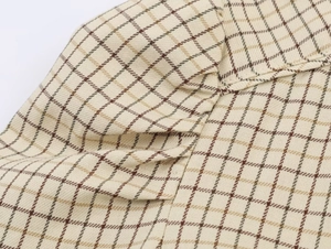 Detailed close-up of the beige plaid shirt collar with brown checkered fabric texture