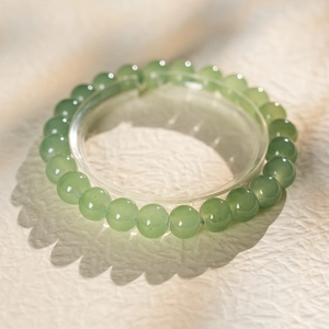 Macro detail of round light green jade beads with smooth polished texture and shadows