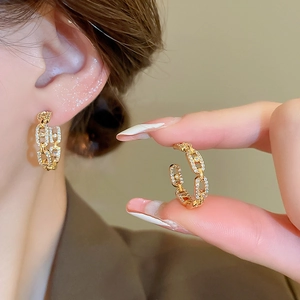 Macro shot of gold plated C-shape chain link earrings featuring sparkling zircon inlay