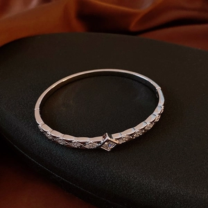 Détail d'un bracelet argenté avec motifs géométriques et pierre centrale carrée