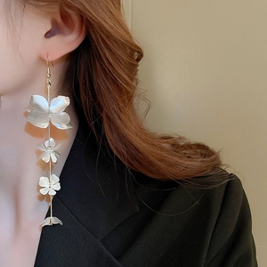 Detail of long tassel earrings featuring three gradient white flowers and gold chains