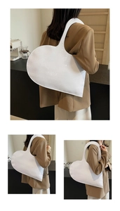 Detail view of white heart-shaped handbag with crocodile pattern texture on a model
