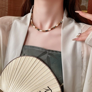 Detail of beaded necklace with natural stone on model in vintage Chinese style