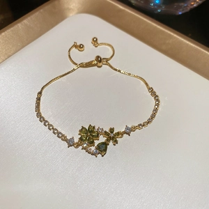 Detail of gold flower bracelet with green gemstone and adjustable sliding clasp