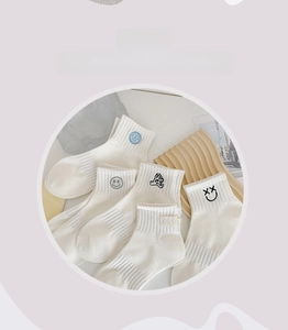 Detailed close-up of white cotton socks with various cute cartoon embroidery patterns