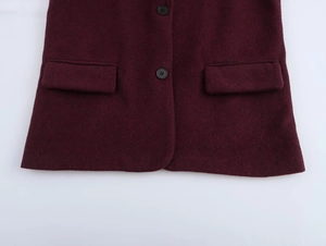 Close-up of wine red blazer with black buttons and symmetrical flap pocket details