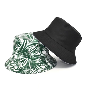 Double-sided bucket hat with green tropical leaf print and solid black cotton finish