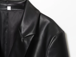 Close-up of the notch lapel and shoulder stitching on a black faux leather blazer jacket