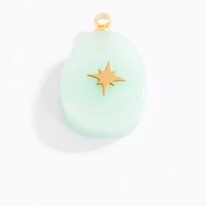 Detail of light green natural stone butterfly pendant with gold star motif and metal frame