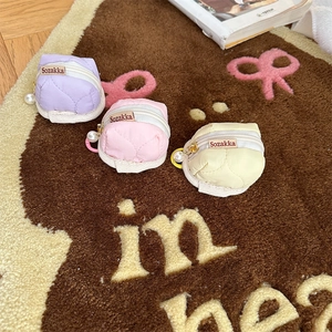 Close-up of quilted macaron-colored pouches with pearl zippers on a plush rug