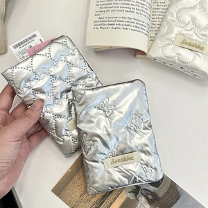 Detail of silver quilted passport holder with bow embroidery and brand logo on top