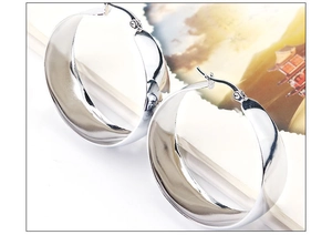 Macro detail of silver wide-band stainless steel hoop earrings on a magazine page