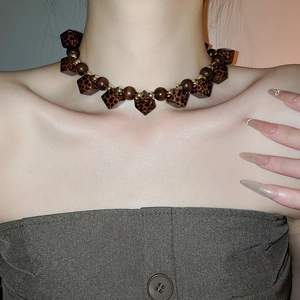 Detail of beaded necklace with dark faceted beads and gold accents worn by a model