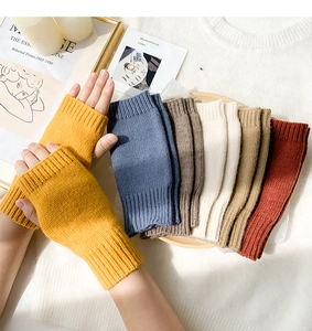 Close-up of knit fingerless gloves in yellow, blue, and brown on a rustic wooden tray