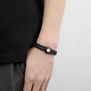 Close-up of a black cuban link bracelet featuring a large clear round gemstone on a wrist