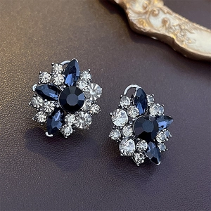 Macro shot of vintage flower stud earrings featuring blue gems and sparkling rhinestones